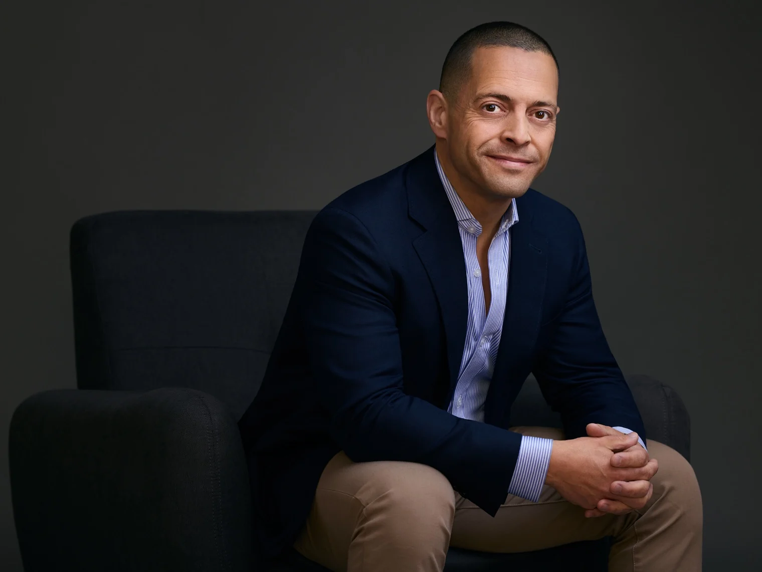 Roddy Awad seated in a chair, wearing a navy blazer